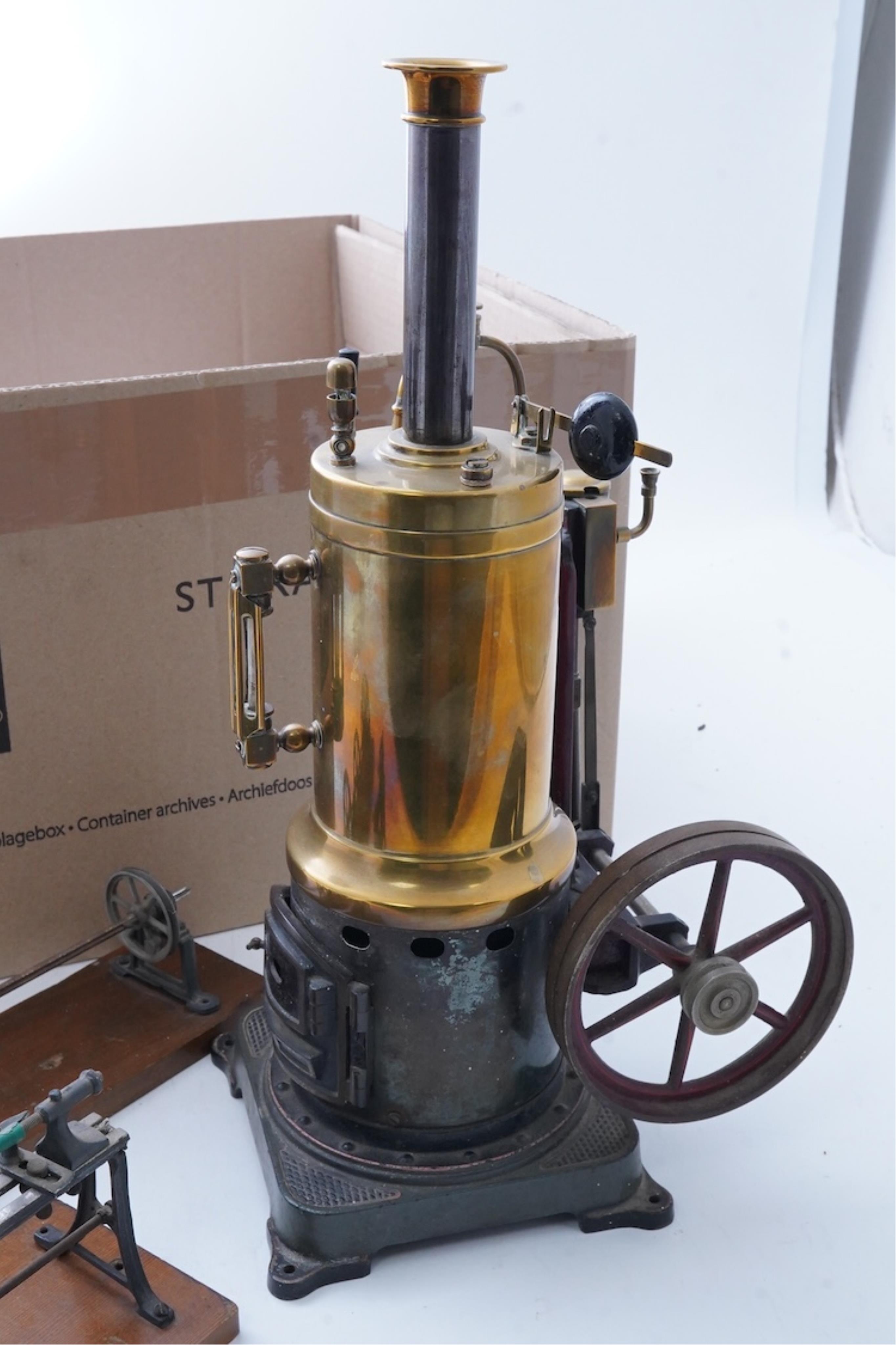 An early 20th century Bing live steam single cylinder vertical stationary engine, of brass, tinplate and cast iron construction, 38cm high, 10.5cm diameter flywheel, complete with the burner, together with a steam plant